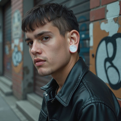 An image of a dark haired man wearing icicle quartz plugs in his stretched ears
